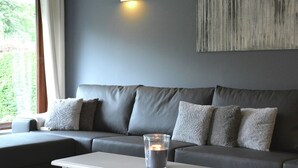 A modern living room with a grey sofa, a white side table, and a lit candle. - Luxurious Holiday Home in Hamoir With Terrace (Hamoir)