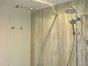 A shower with a rain shower head and a handheld showerhead, mounted on a wall with a textured, light-colored finish. - Luxurious Holiday Home in Hamoir With Terrace (Hamoir)