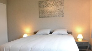 A neatly made bed with white linens, two bedside lamps, and a painting on the wall. - Luxurious Holiday Home in Hamoir With Terrace (Hamoir)