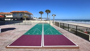 Une table de jeu de shuffleboard offrant une vue dégagée sur l’océan et la plage en arrière-plan.