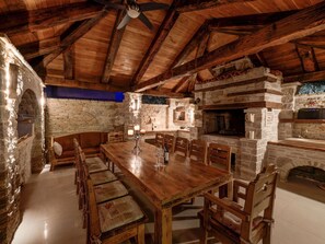 Ein rustikaler Essbereich mit Holztisch und -bänken, Steinwänden und einem Steinkamin.