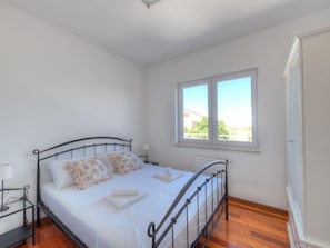 Ein Schlafzimmer mit einem Bett, zwei Nachttischen, einem Fenster und einer Heizung.