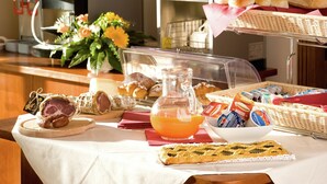 A breakfast buffet with pastries, bread, and a fruit punch pitcher.
