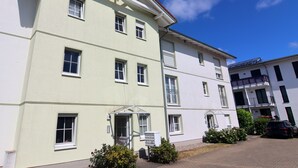 Ein mehrstöckiges Gebäude mit heller Fassade, zahlreichen Fenstern und einem gut sichtbaren Eingang.