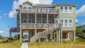 Une maison à deux étages dotée d’une terrasse en bois et d’un escalier menant à l’étage supérieur.