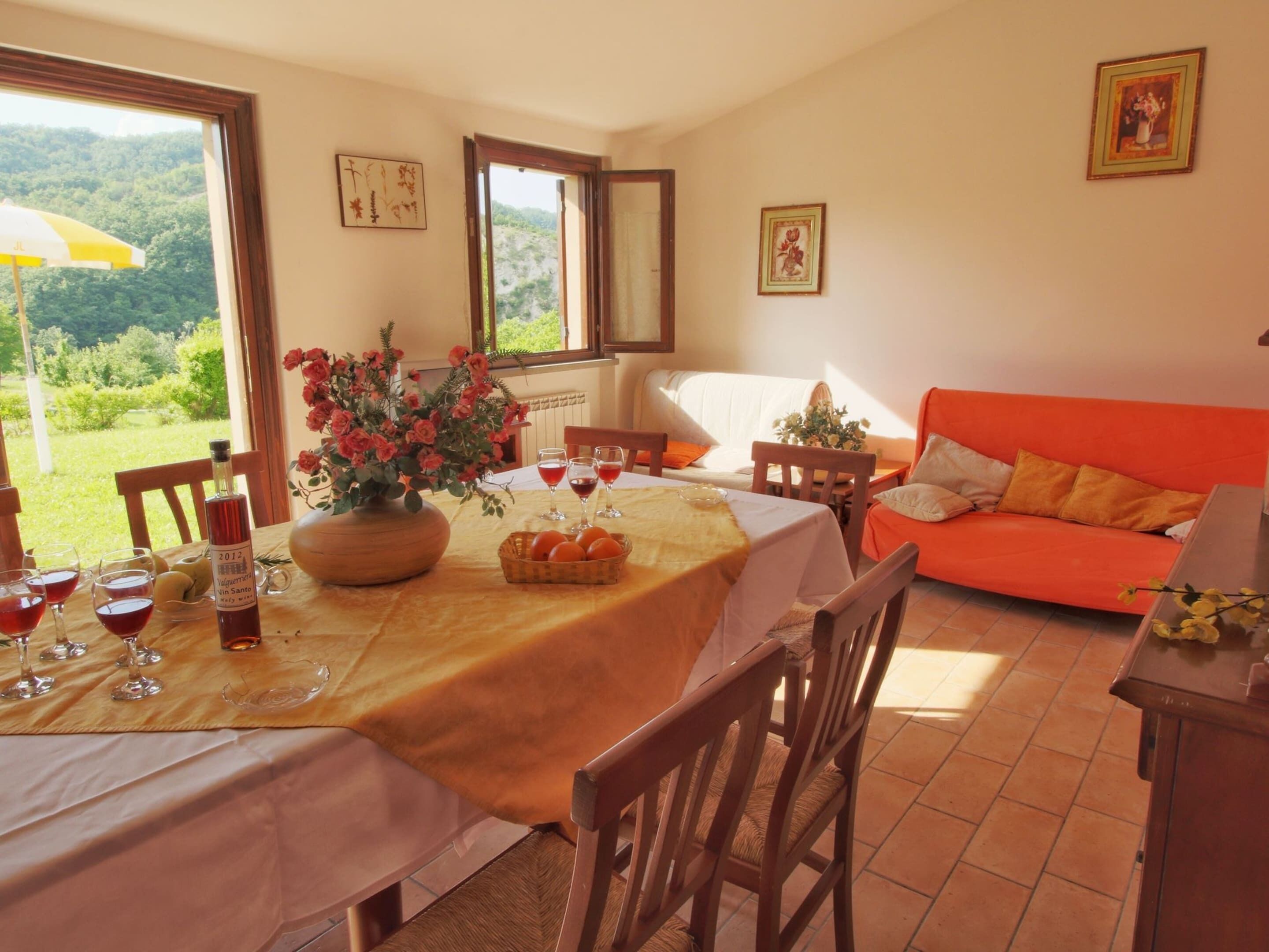 Un espace repas avec une table mise pour le repas, des chaises, un canapé et une vue sur l’extérieur.
