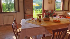A dining area with a table set for four, a vase of flowers, and a bottle of wine.