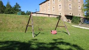 A grassy area with a swing set and a large stone building in the background.