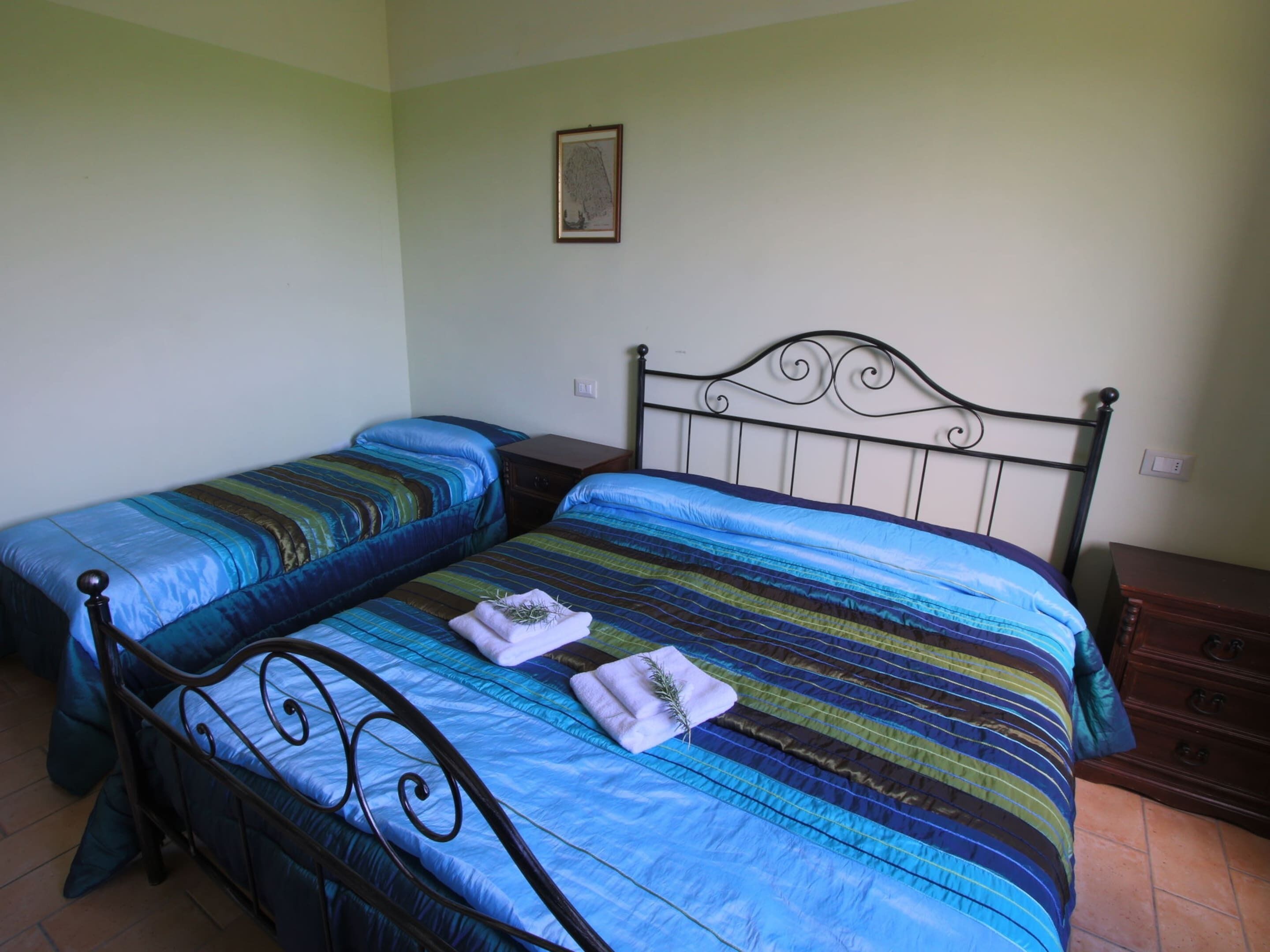 A bedroom with two single beds, each with a blue striped bedspread and matching pillows.