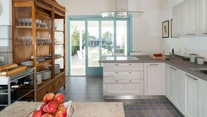 Eine moderne Küche mit weißen Schränken, einer Glastür zum Patio und einer Obstschale auf der Arbeitsfläche.