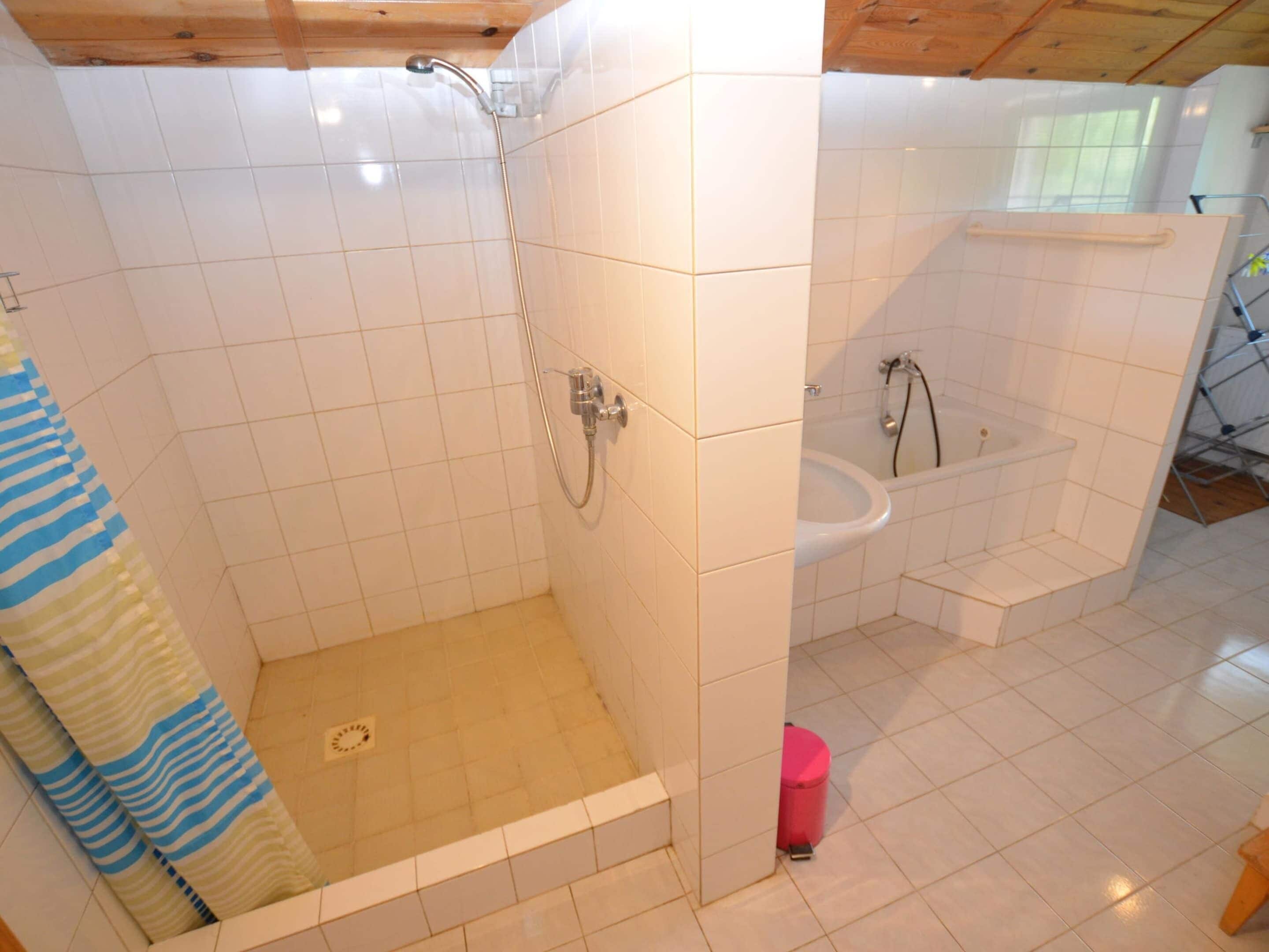 A bathroom with white tiled walls, a shower, a sink, and a bathtub.