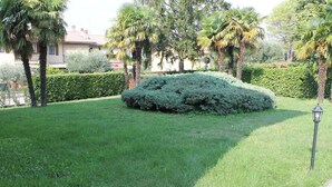 A well-maintained lawn with a neatly trimmed bush, a street lamp, and a stop sign in the background.