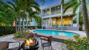 A two-story building with a swimming pool, outdoor seating, and a fire pit. - Siesta Soul | Multilevel Home Located in Siesta Key Village w/ Private Pool, Fire Pit, Walk to Beach (Siesta Key)