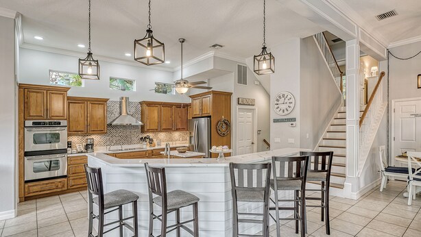 A spacious kitchen with wooden cabinets, stainless steel appliances, and a central island with bar stools. - Siesta Soul | Multilevel Home Located in Siesta Key Village w/ Private Pool, Fire Pit, Walk to Beach (Siesta Key)