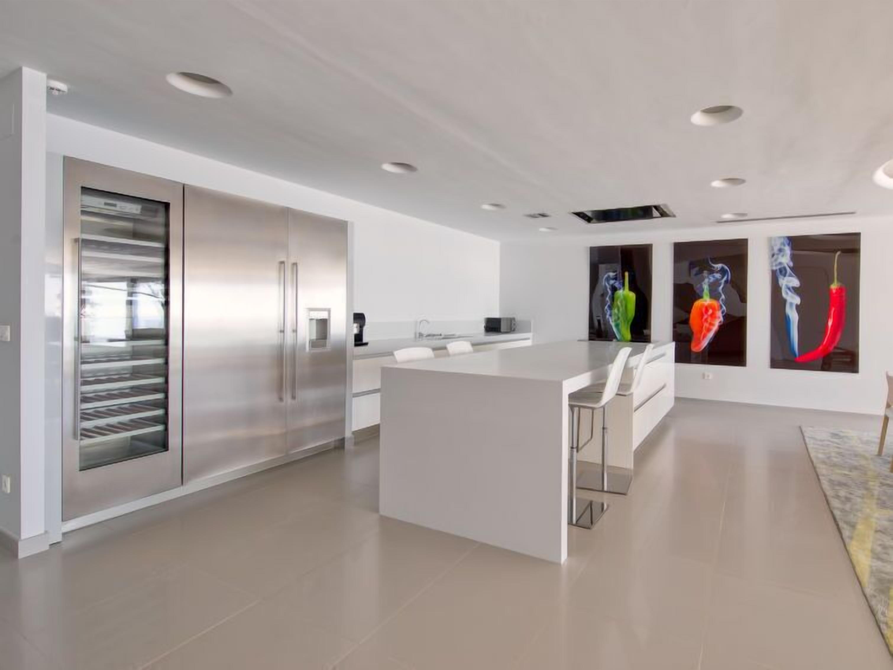 A modern kitchen with a central island, stainless steel appliances, and a large window.