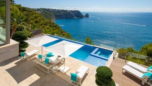 A modern outdoor pool area with lounge chairs and a view of the sea. - Emma on the Roc by Interhome (Jávea)