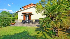 A house with a patio, a table with chairs, and a large umbrella. - Belvilla by OYO Villa Mimosa (Cortona)