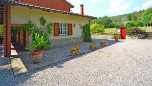 A rustic house with a stone foundation, a tiled roof, and a gravel driveway. - Belvilla by OYO Villa Mimosa (Cortona)