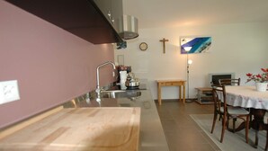 A kitchen with a stainless steel sink, wooden countertop, and a dining area with a table and chairs. - Apartment in Blatten With Mountain Views & Open Kitchen (Blatten)