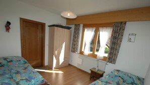 A room with two beds, a wooden ceiling, a window with curtains, and a radiator. - Apartment in Blatten With Mountain Views & Open Kitchen (Blatten)