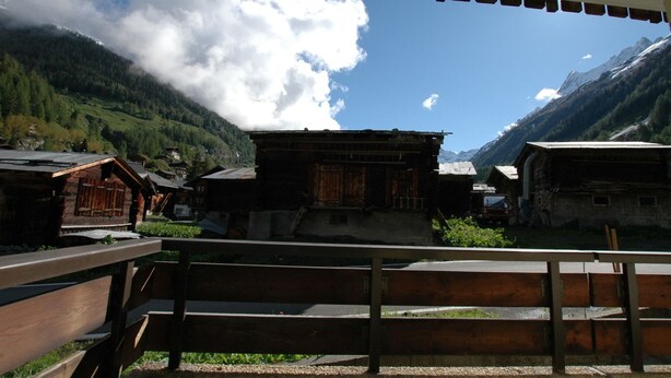 A traditional wooden building with a sloped roof, surrounded by a mountainous landscape and a clear sky. - Apartment in Blatten With Mountain Views & Open Kitchen (Blatten)