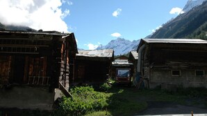 A rustic mountain village with traditional wooden buildings, a dirt road, and a truck parked in front. - Apartment in Blatten With Mountain Views & Open Kitchen (Blatten)