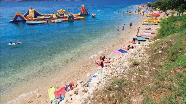 A beach with inflatable structures and people sunbathing. - Scenic Holiday Home in Bibinje near Sea (Bibinje)