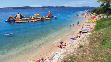 A beach with inflatable structures and people sunbathing.