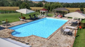 Une piscine rectangulaire bordée de pierres, entourée de chaises longues et de parasols.