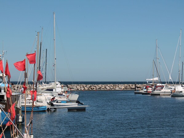 A marina with multiple sailboats docked, a rocky breakwater in the background, and calm water. - Lovely Apartment in Neubukow near Sea (Neubukow)