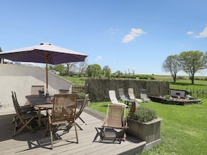 A wooden deck with outdoor furniture, including a table and chairs, and a large umbrella providing shade. - Cushy Holiday Home With Fenced Garden (Tenneville)
