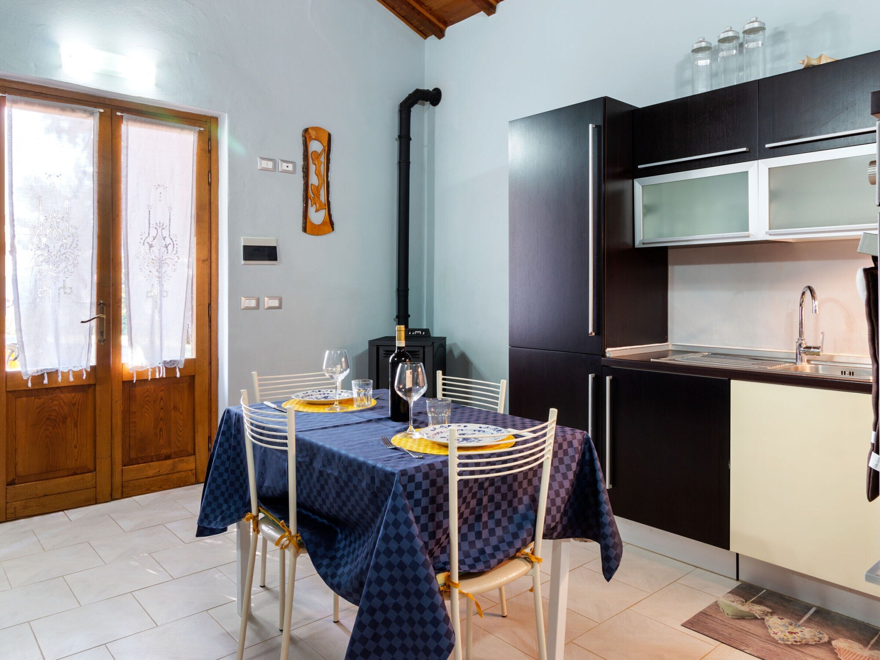 A compact kitchen with a dining area, featuring a table set for two, a built-in oven, and a sink.