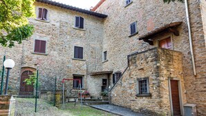 A stone building with multiple windows and a staircase leading to a door. - Countryside Home in Arezzo With Pool (Arezzo)