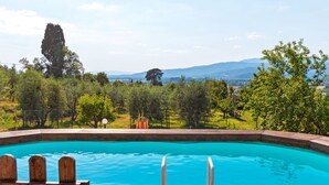 A swimming pool with a wooden deck and a view of a countryside landscape. - Countryside Home in Arezzo With Pool (Arezzo)