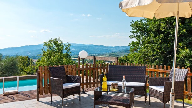 An outdoor patio with wicker furniture, a pool, and a scenic view of mountains. - Countryside Home in Arezzo With Pool (Arezzo)