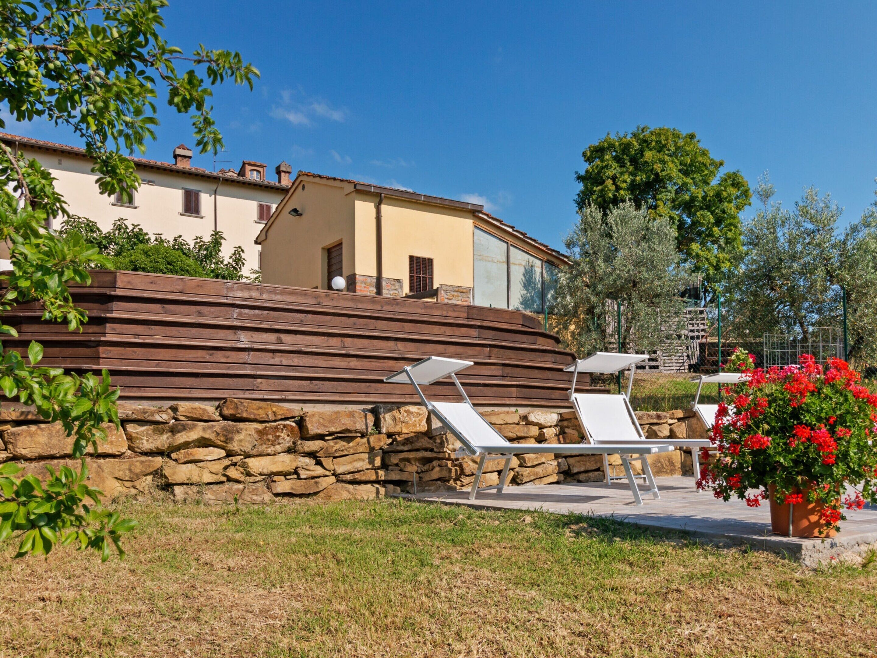 Un muro de piedra con dos sillones blancos en un jardín.
