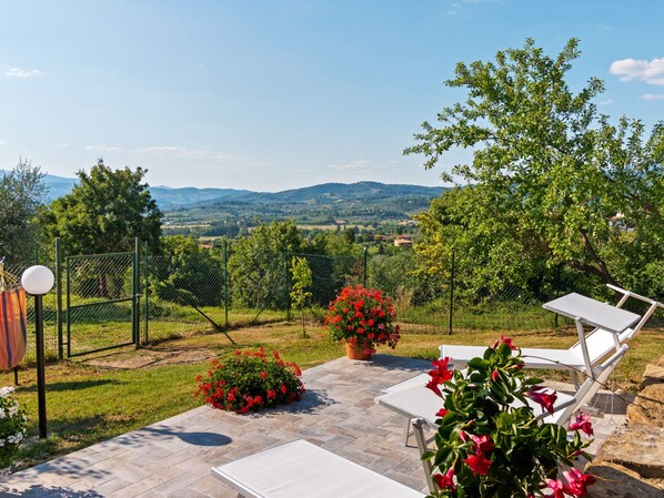 A patio with outdoor seating, a fenced garden, and a view of distant hills. - Countryside Home in Arezzo With Pool (Arezzo)