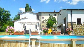 A swimming pool with a wooden deck, a white gazebo, and potted flowers. - Countryside Home in Arezzo With Pool (Arezzo)