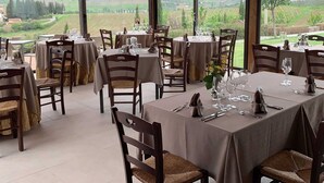 Um restaurante com várias mesas postas para refeições, cada uma com cadeiras e louças.