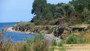 A coastal landscape with a sandy beach, rocky cliffs, and dense greenery. - Modernes Ferienhaus mit Garten in Kagsdorf (Bastorf)