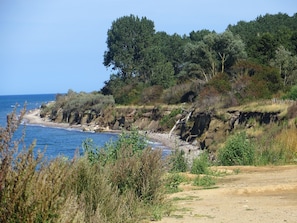 A coastal landscape with a sandy beach, rocky cliffs, and dense greenery. - Modernes Ferienhaus mit Garten in Kagsdorf (Bastorf)