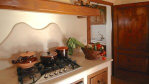 A kitchen with a gas stove, two pots, a basket of vegetables, and a wooden cabinet. - Agriturismo near Cortona with Spacious Garden & Swimming Pool (Cortona)