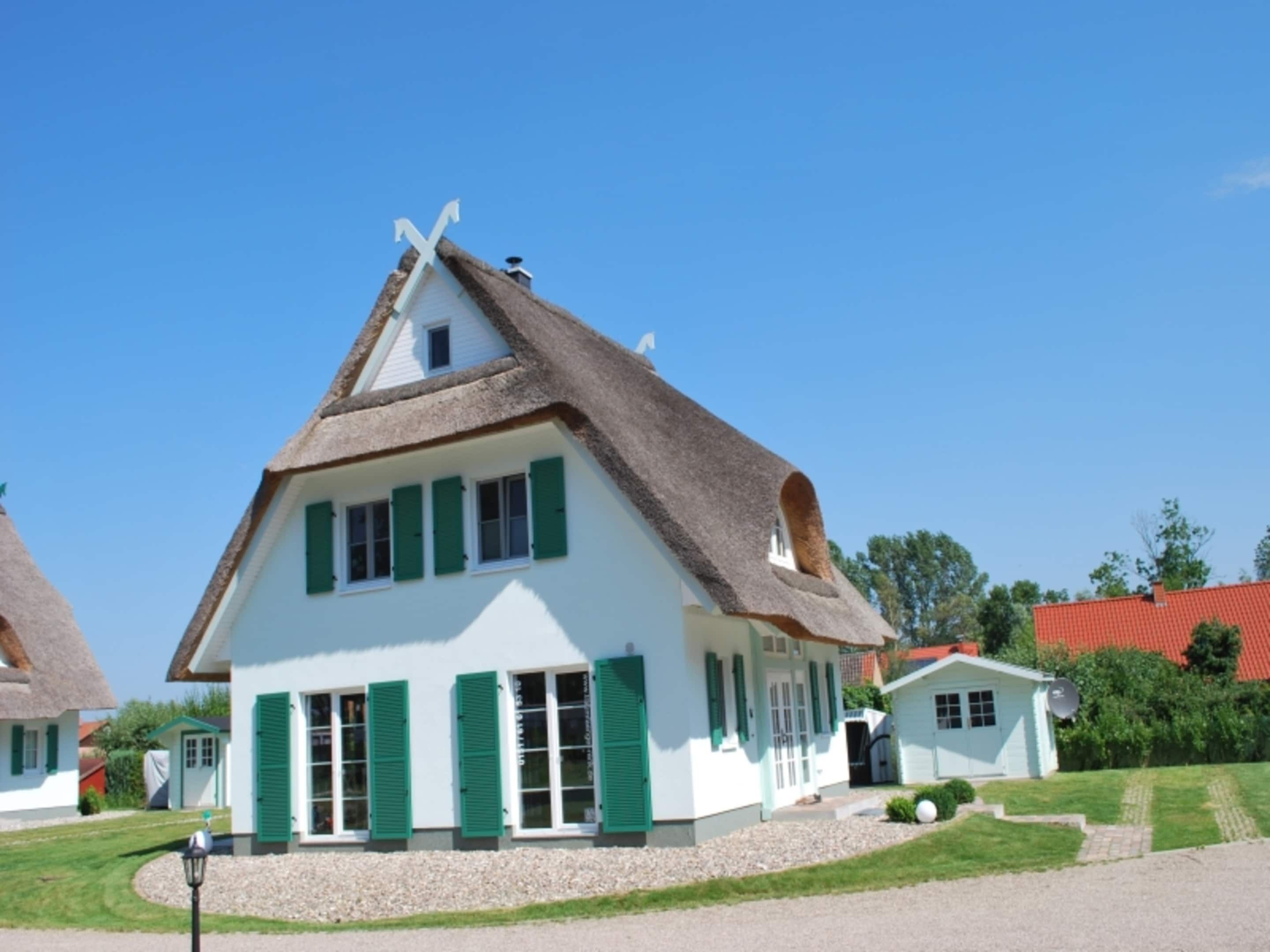 Ein traditionelles Haus mit einem steilen Dach, weißen Wänden und grünen Fensterläden.
