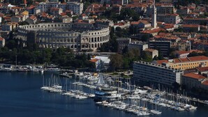 A coastal cityscape with a historic building, marina, and residential area.