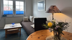 A living room with a wooden coffee table, a sofa, a lamp, and a window with blinds. - Cozy Apartment in Zingst Germany near Beach (Zingst)