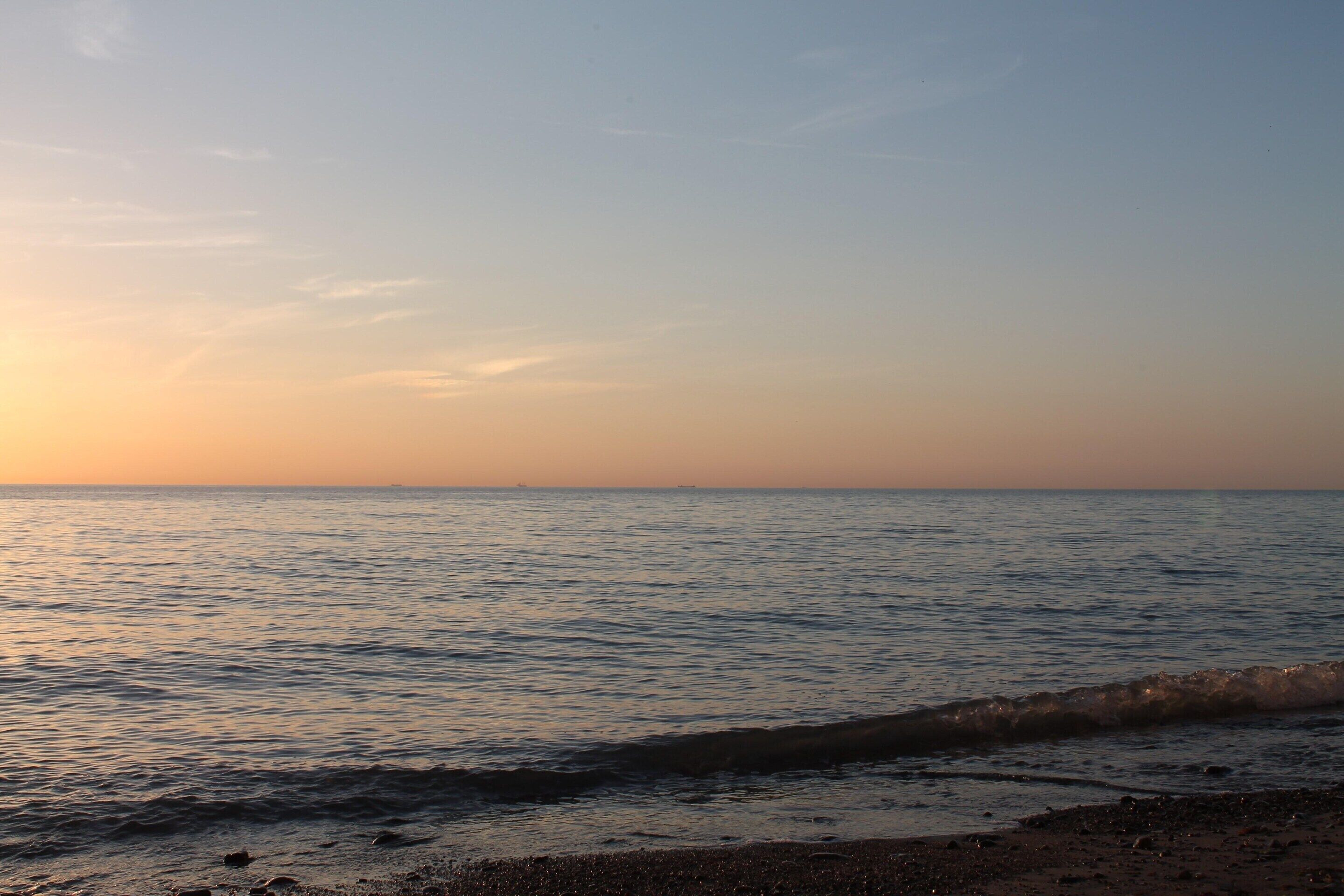 En strand med stilla vatten och en klar himmel.