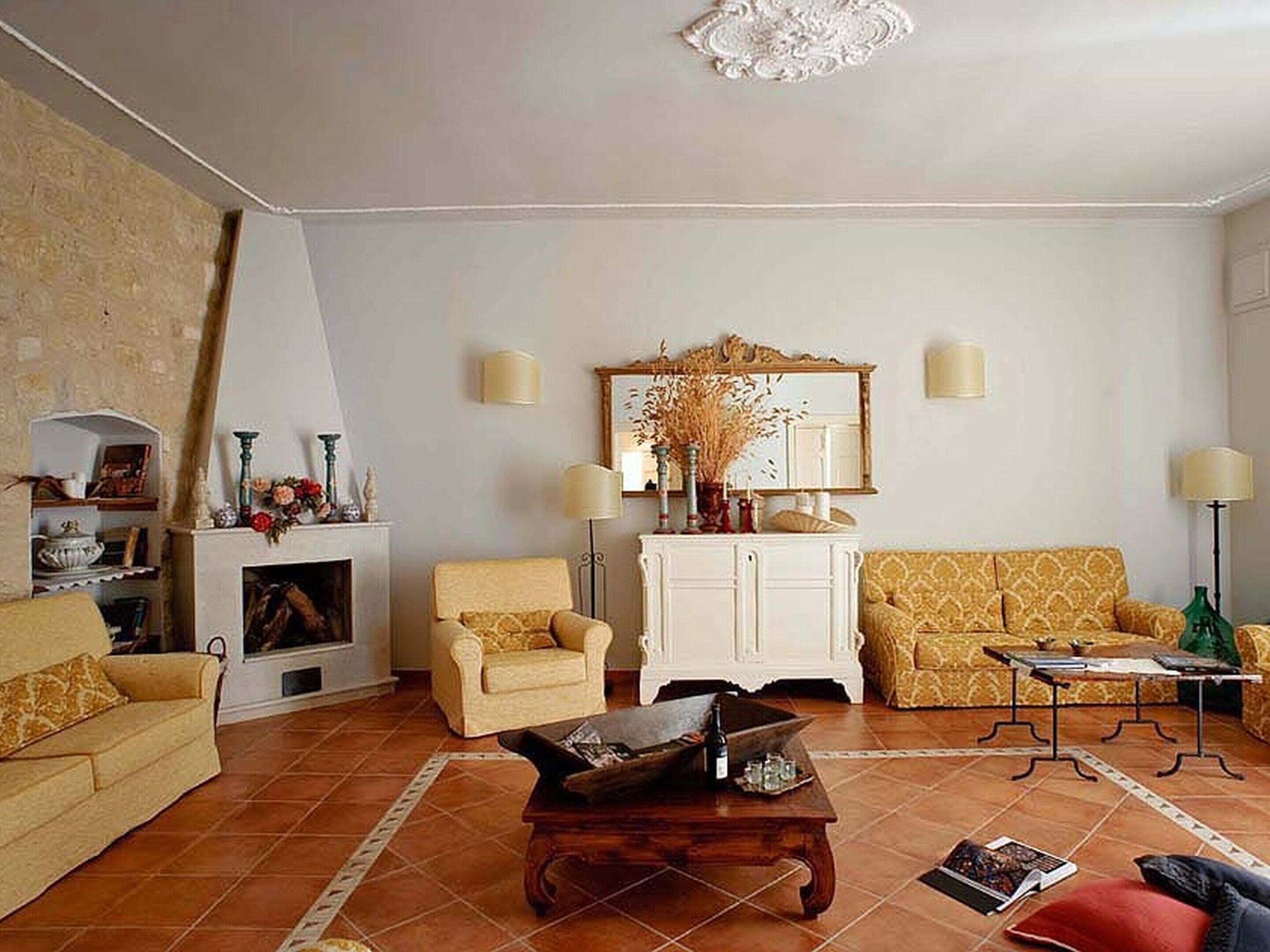 Una sala de estar con chimenea, dos sillones, un sofá y una mesa de centro.