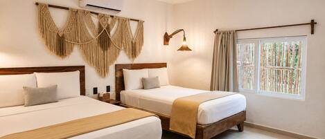 Habitación de hotel con dos camas, aire acondicionado montado en la pared, un tapiz de macramé, una lámpara de pie y una ventana con cortinas.