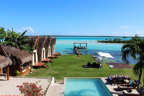 Ein Resort mit Pool, Liegestühlen und Blick aufs Meer.