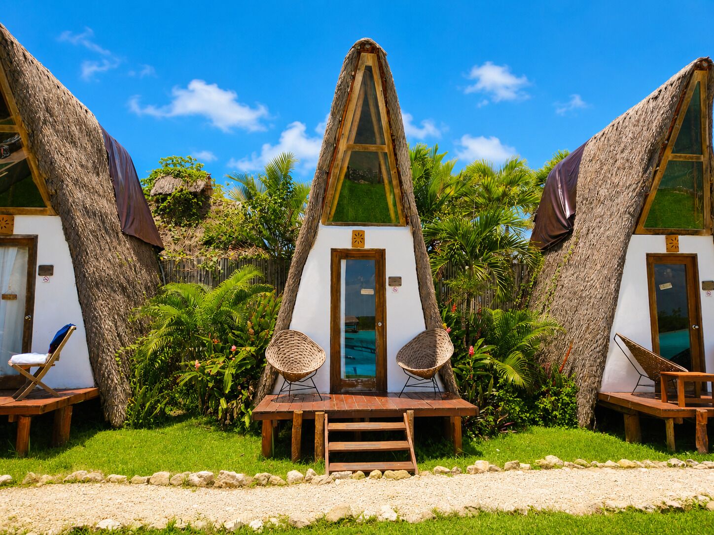 A bungalow with a thatched roof, a wooden deck, and a small pool.